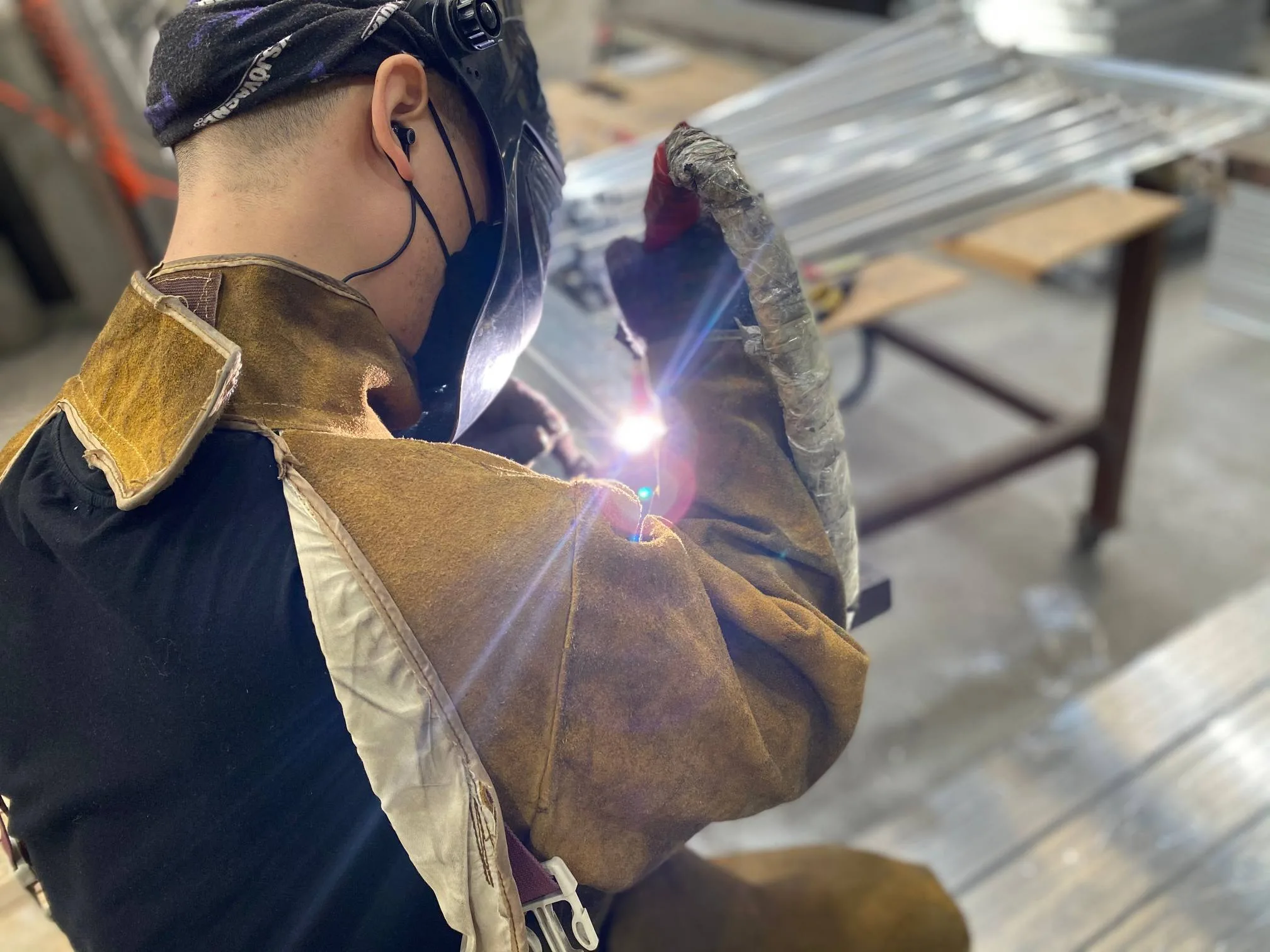 Professional welder working on Aluminum Alloy frames. Factory production line ensuring structural integrity for off-road gear.